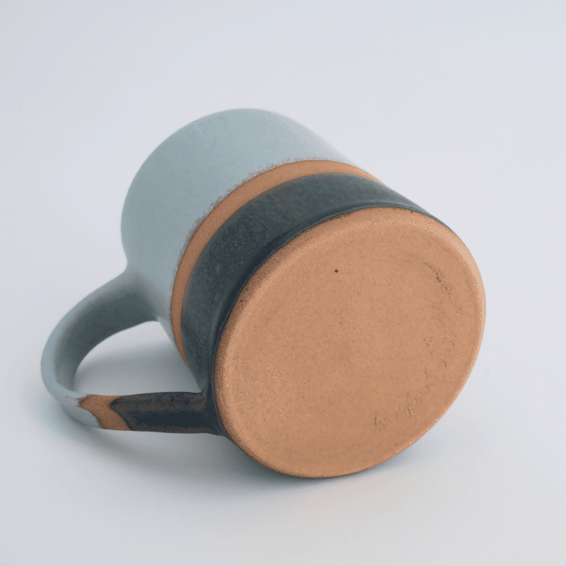 Mug en grès rouge, émaillé vert d'eau sur la partie supérieure et noir sur la partie inférieure, avec une bande de séparation non émaillée laissant la terre apparente.