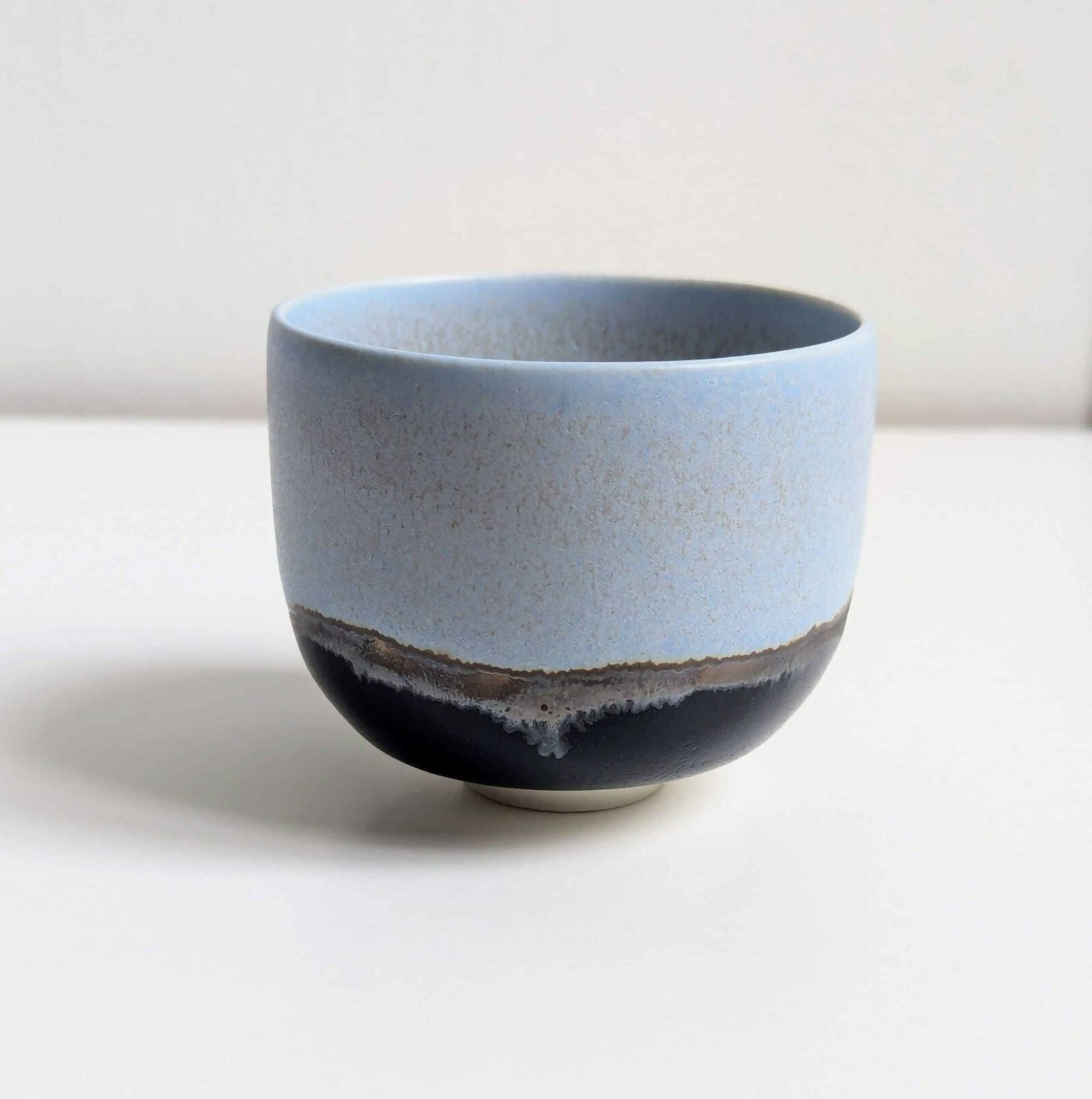 Tasse en porcelaine, émail bleu mat/satiné à l’intérieur et à l'extérieur sur la partie supérieure, émail noir brillant sur la partie inférieure, séparés par une ligne d'émail métallisé.