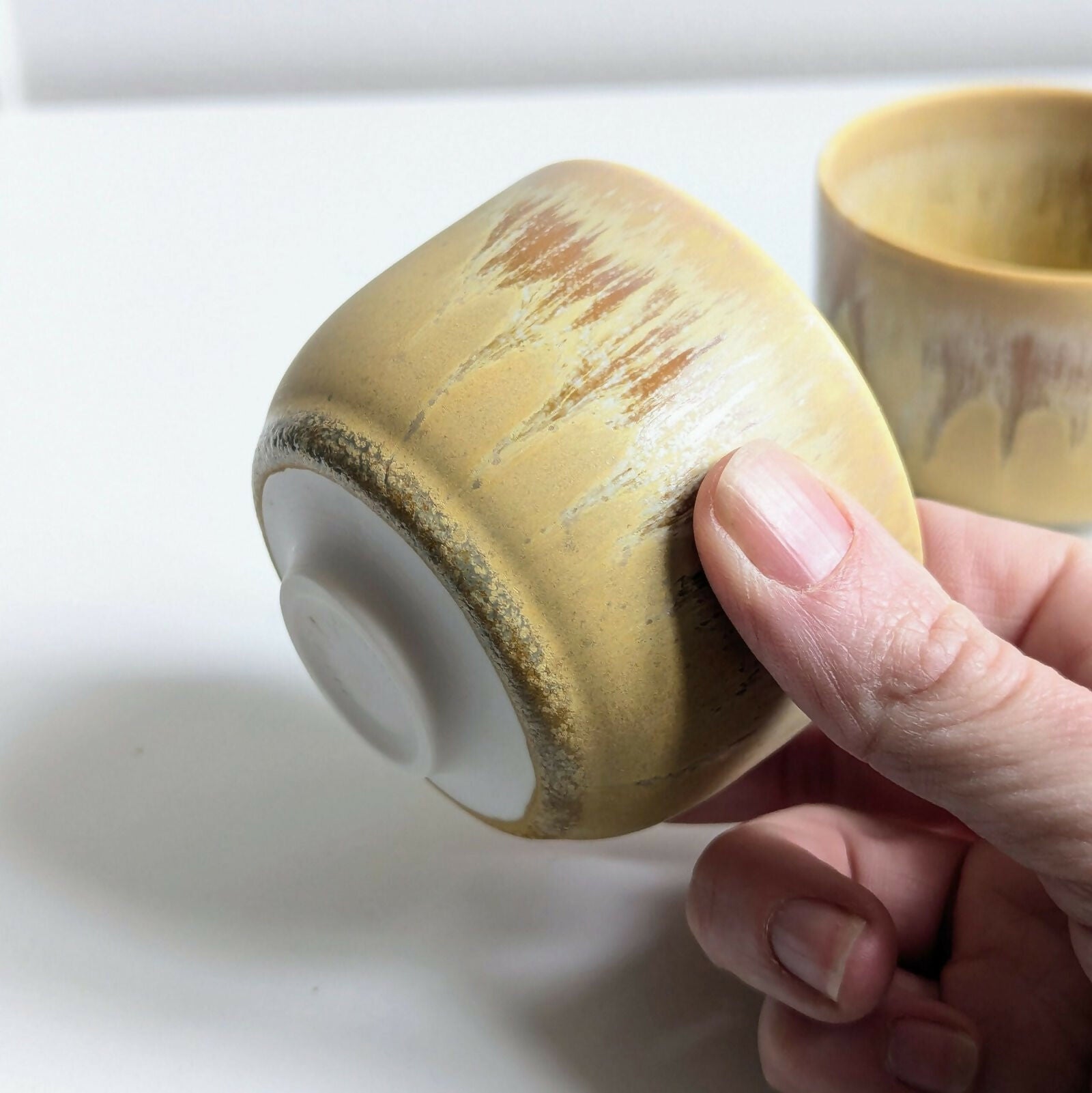 Tasse artisanale en porcelaine, émail jaune mat nuancé par une superposition d'un émail brillant à base de cendres de bois.