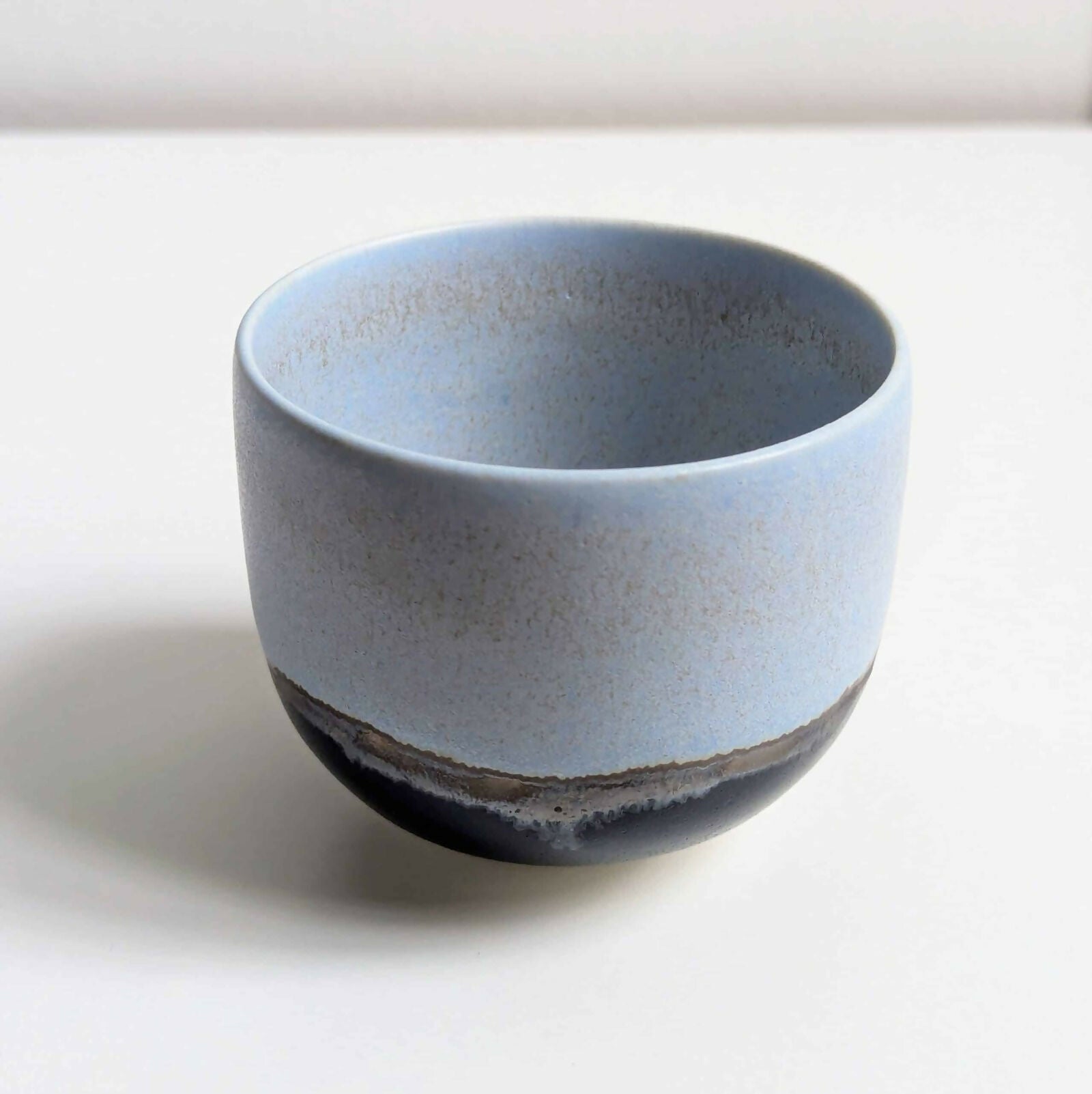 Tasse en porcelaine, émail bleu mat/satiné à l’intérieur et à l'extérieur sur la partie supérieure, émail noir brillant sur la partie inférieure, séparés par une ligne d'émail métallisé.