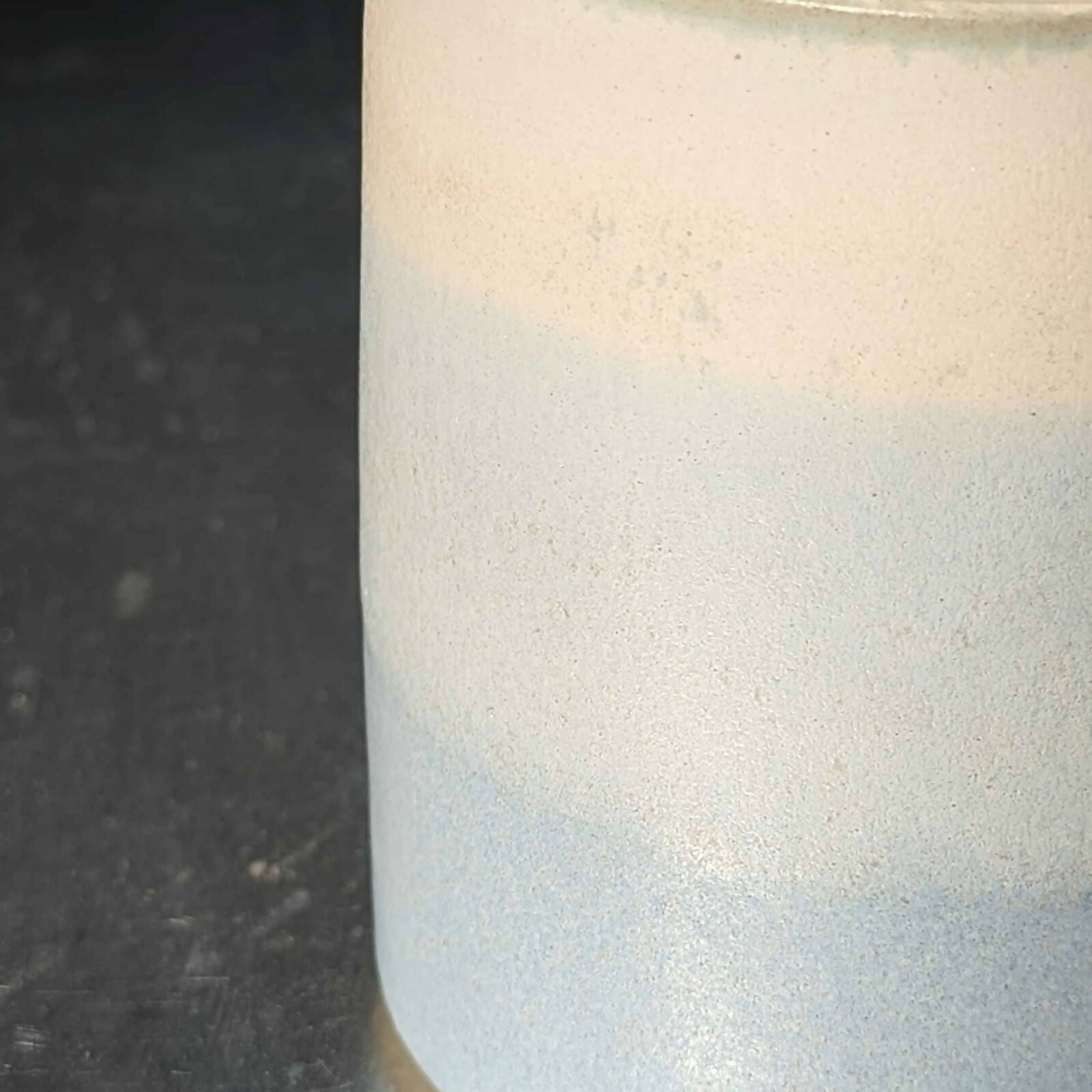 Un mug en grès blanc, tourné et ansé à la main, et émaillé en dégradé de bleu et blanc.