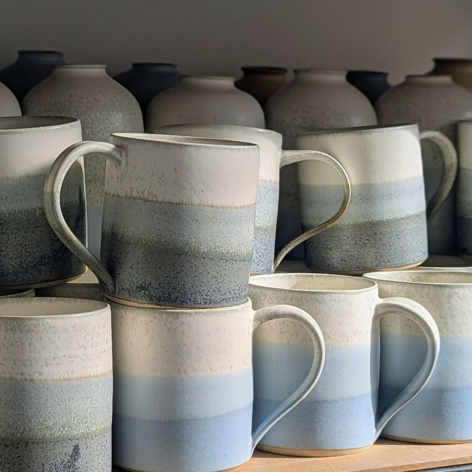 mugs en grès blanc, tournés et ansés à la main, et émaillé en dégradé de bleu et blanc ou gris et blanc