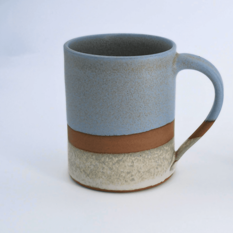 Mug en grès rouge, émaillé bleu sur la partie supérieure et blanc sur la partie inférieure, avec une bande de séparation non émaillée laissant la terre apparente.